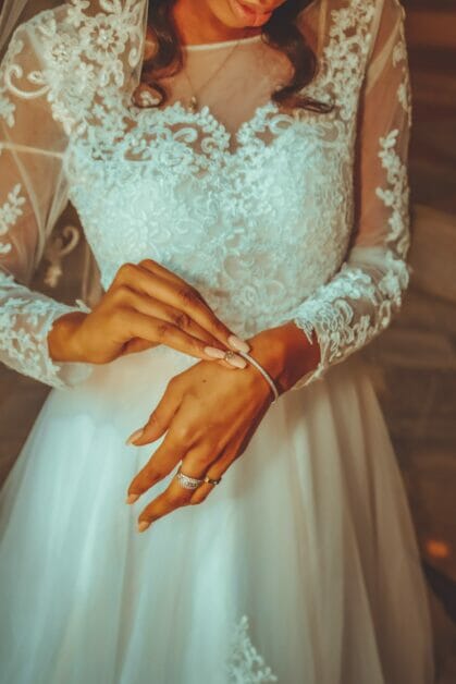 a bride in her wedding dress putting on her bracelet