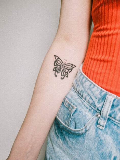 a butterfly sketch tattoo on the woman's inner right arm