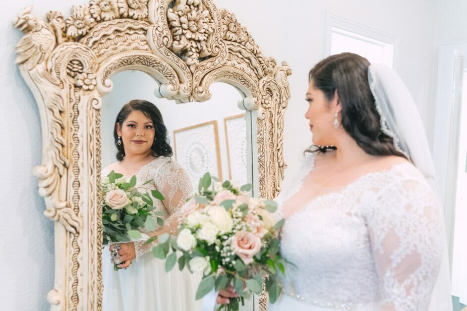 a plus-size woman in her wedding dress looking at the mirror