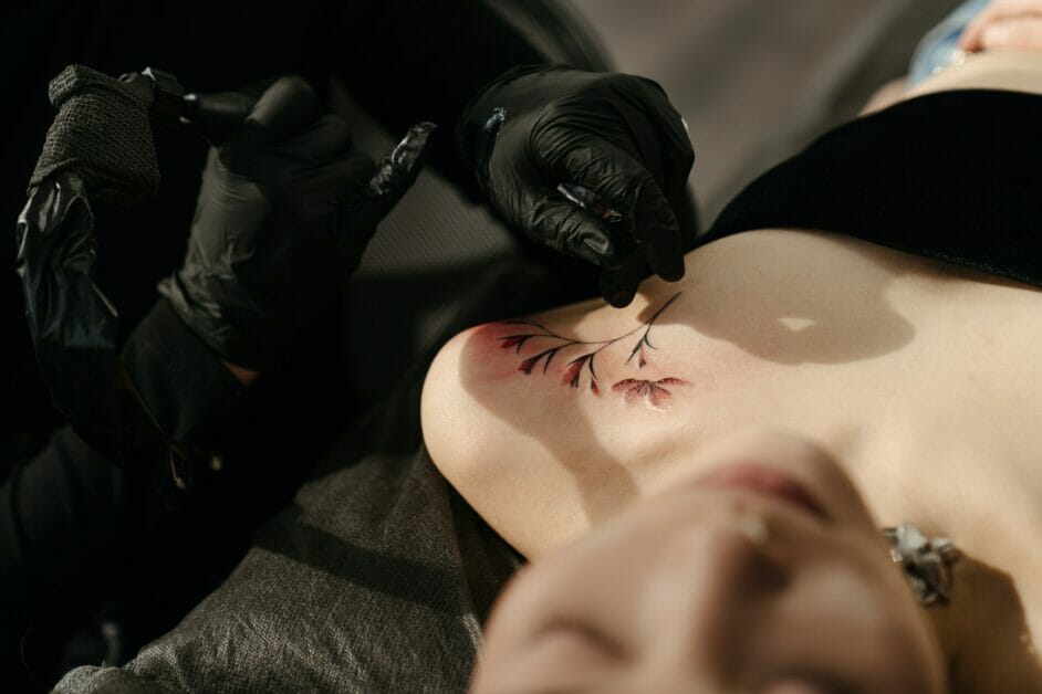 a tattoo artist performing ink on a woman's left clavicle area