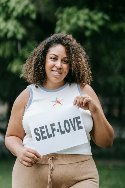 a woman holding a bond paper with SELF-LOVE printed on it