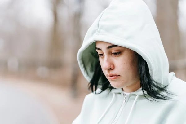 a woman wearing her hoodie looking at nothingness