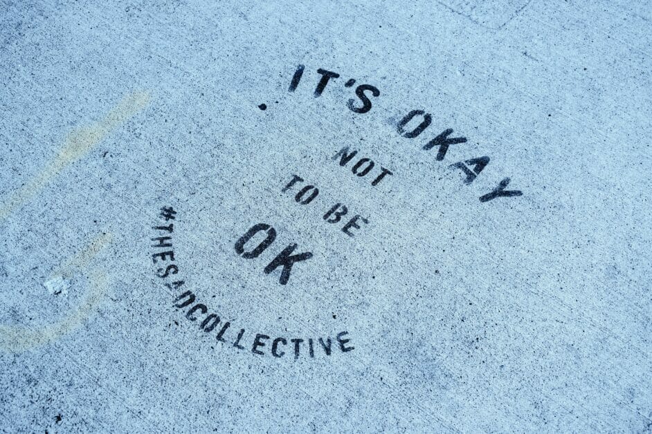 "it's okay not to be okay" written on the floor cement