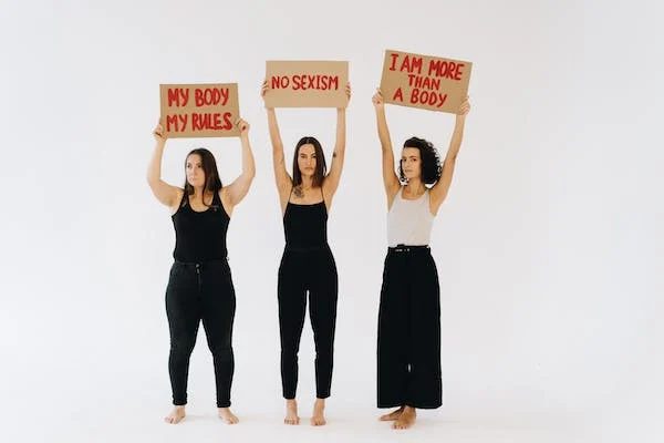 three woman holding up placards about body positivity