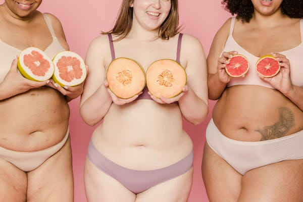 three woman in shapewear holding fruits