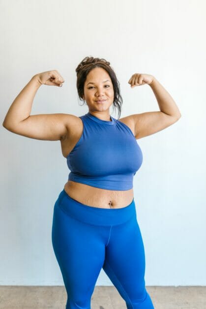 woman in royal blue gym outfit lifting her arms