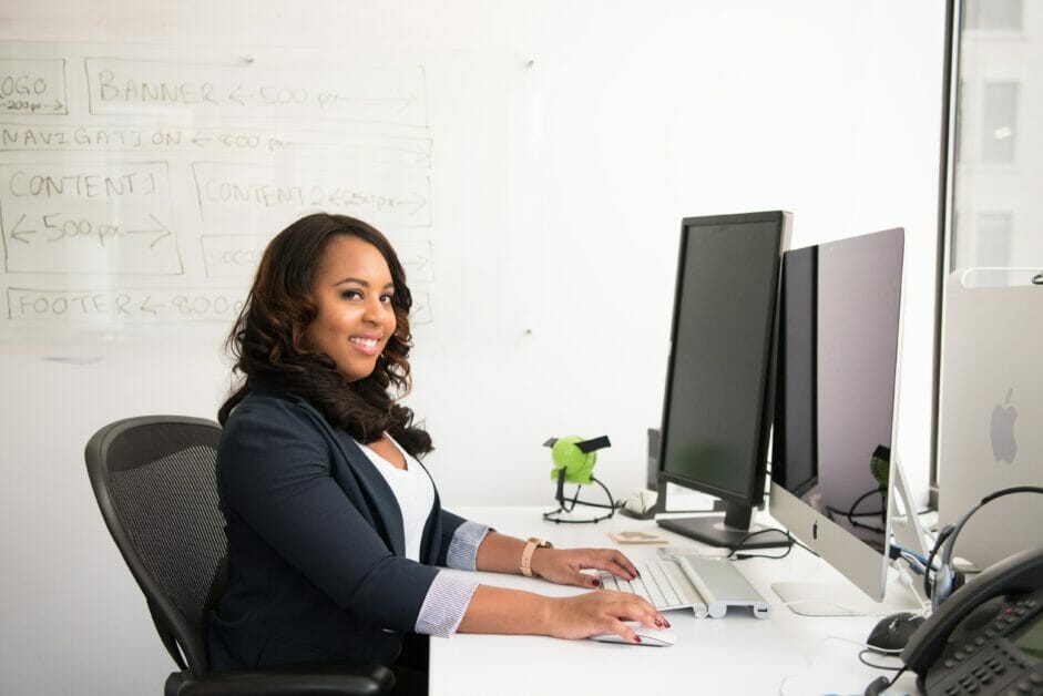 woman smiling seating on her working area with her computer on