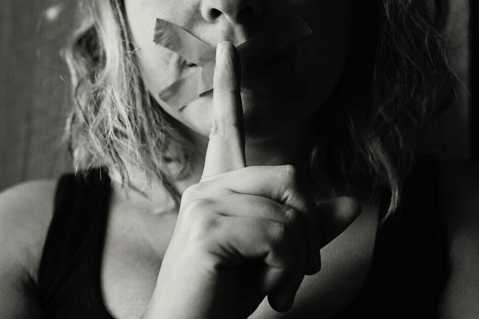 woman with plaster on her mouth with a hand sign of silence
