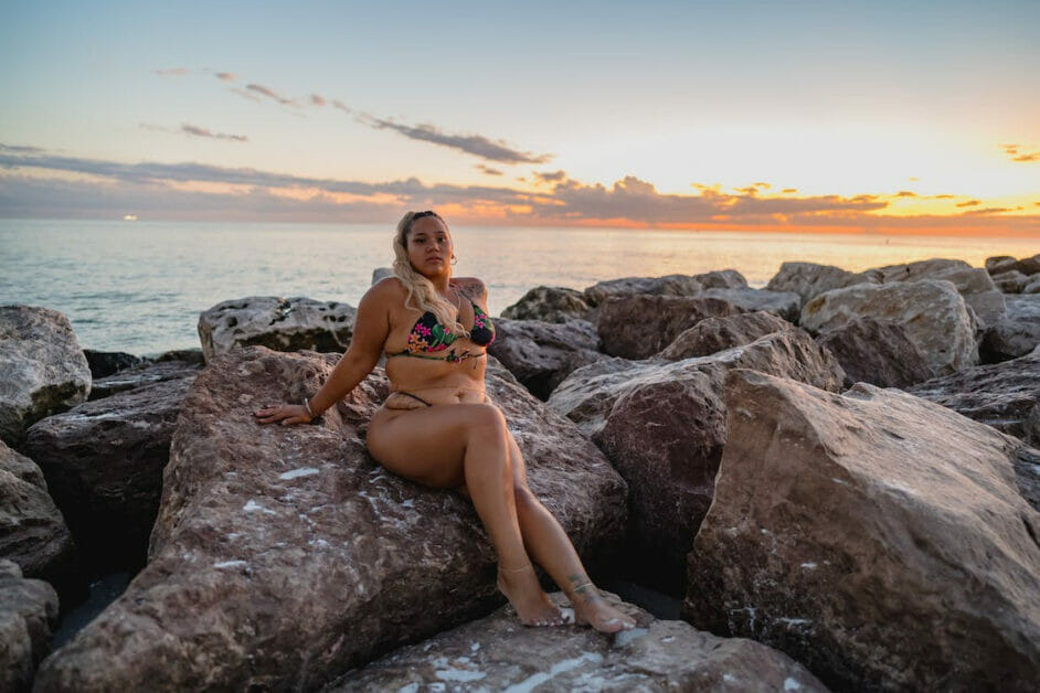 a plus-size woman on her two-piece swimsuit sitting at one of the stones among the boulders