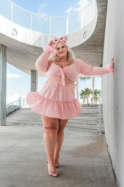 a plus-size woman wearing a pink dress with ruffles on the hem