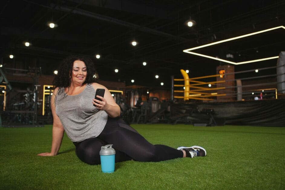 a plus size woman capturing a selfie while sitting on the gym